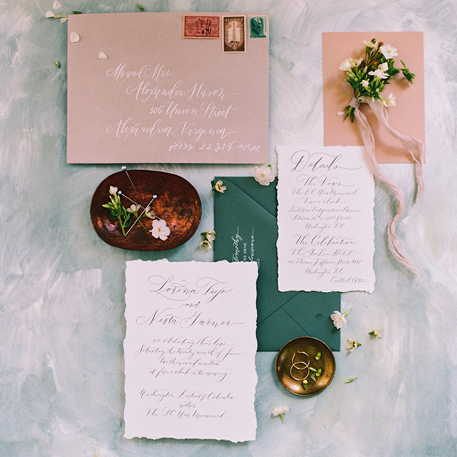 Custom, luxury wedding invitation suite with white hand calligraphy. Rose and emerald green envelopes with custom hand calligraphy invitation with torn edges by expert wedding stationery designer, Laura Hooper Design House.