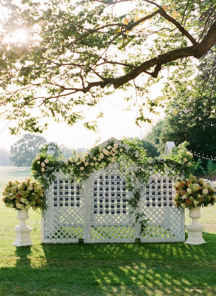 Large lattice wedding escort card display with lush floral arrangements for outdoor cocktail hour in washington dc. Hand calligraphy escort cards. Laura Hooper Design House. 