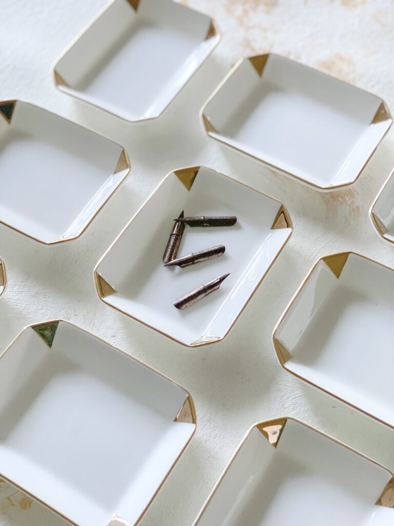 Pointed pen calligraphy nibs in ink dishes. Laura Hooper Design House.