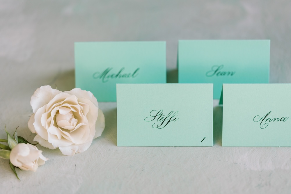 Simple green escort cards with calligraphy names for winter wedding. Laura Hooper Design House. 