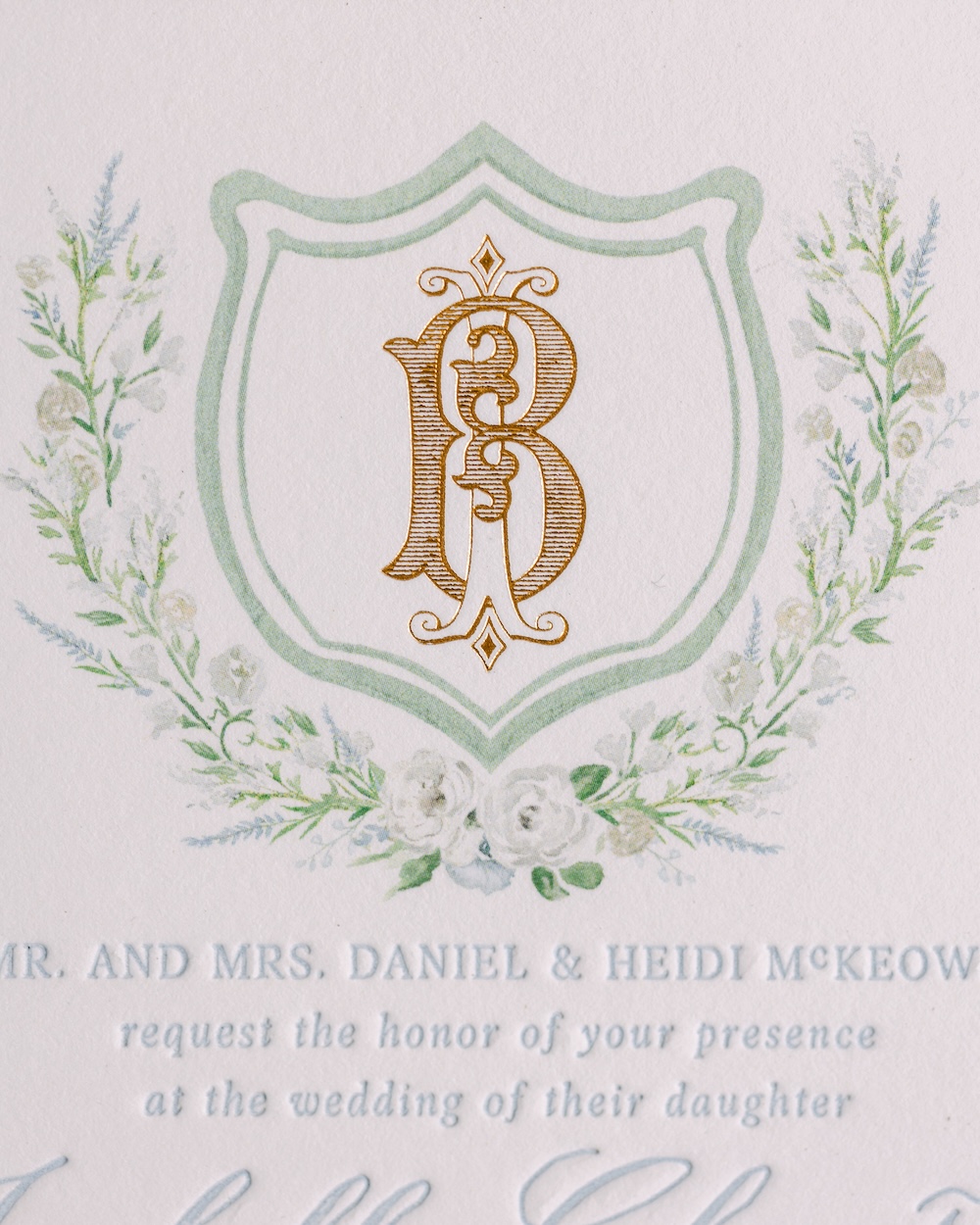 Watercolor floral wreath with gold leaf monogram crest wedding invitation. Laura Hooper Design House.